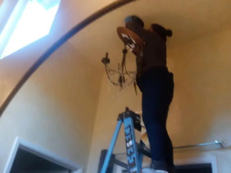 Electrician installing a chandelier in a Lynn Haven residence